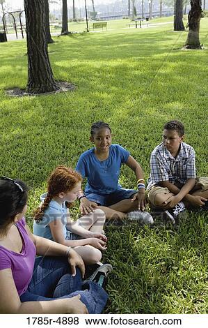 Children sitting in a circle on the grass with their teacher at a park View Large Photo Image Stock Photo - Children sitting in a circle on the grass with their teacher at a park. Fotosearch