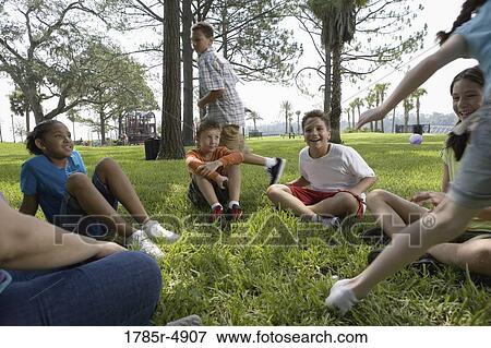 Children sitting in a circle on the grass with their teacher while a boy and agirl run around them View Large Photo Image Stock Photo - Children sitting in a circle on the grass with their teacher while a boy and agirl run around them. Fotosearch