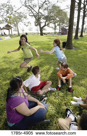 Children sitting in a circle on the grass with their teacher while two girls run around them View Large Photo Image Stock Photography - Children sitting in a circle on the grass with their teacher while two girls run around them. Fotosearch