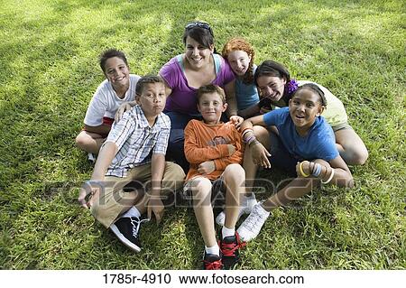 Children with their teacher sitting on the grass at a park View Large Photo Image Stock Image - Children with their teacher sitting on the grass at a park. Fotosearch