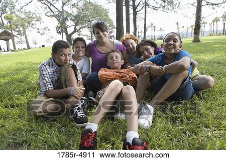 Children with their teacher sitting on the grass at a park View Large Photo Image Stock Image - Children with their teacher sitting on the grass at a park. Fotosearch