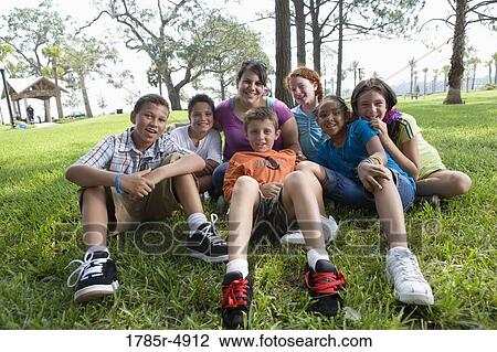 Children with their teacher sitting on the grass at a park View Large Photo Image Stock Image - Children with their teacher sitting on the grass at a park. Fotosearch