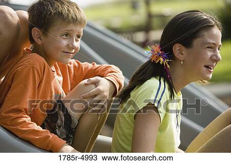Close-up of a boy and a girl sitting on a slide at a playground View Large Photo Image Stock Image - Close-up of a boy and a girl sitting on a slide at a playground. Fotosearch