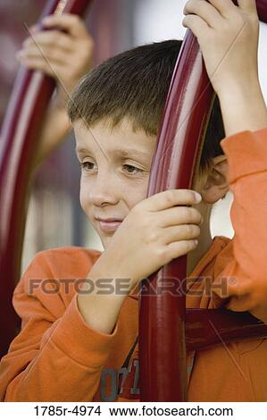 Close-up of a boy climbing on monkey bars at a playground View Large Photo Image Picture - Close-up of a boy climbing on monkey bars at a playground. Fotosearch