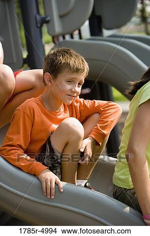 Close-up of a boy sitting on a slide at a playground View Large Photo Image Picture - Close-up of a boy sitting on a slide at a playground. Fotosearch
