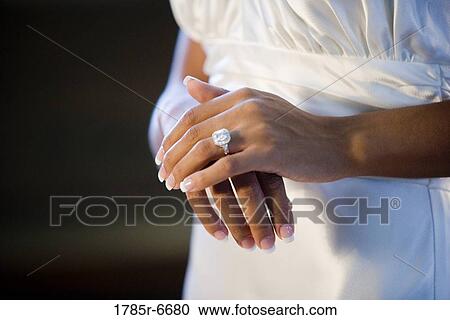 Stock Image - Close-up of a brides hands with a large diamond ring on ring finger. Fotosearch