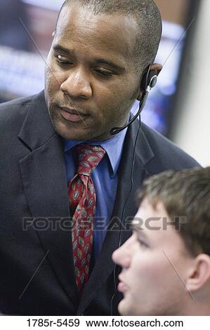 Close-up of a businessman with headset with colleague in foreground View Large Photo Image Stock Photo - Close-up of a businessman with headset with colleague in foreground. Fotosearch