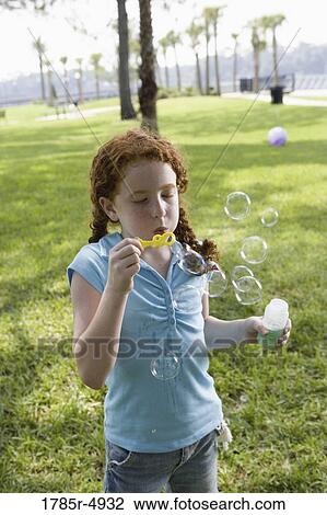 Close-up of a girl blowing bubbles at a park View Large Photo Image Stock Image - Close-up of a girl blowing bubbles at a park. Fotosearch