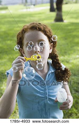 Close-up of a girl blowing bubbles at a park View Large Photo Image Stock Image - Close-up of a girl blowing bubbles at a park. Fotosearch