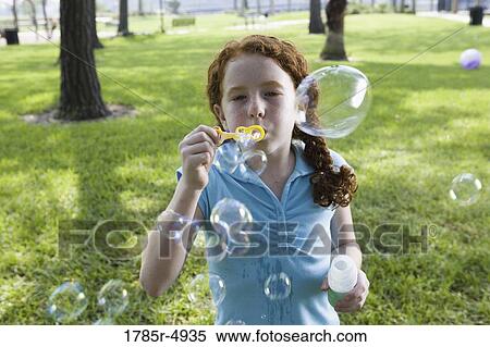 Close-up of a girl blowing bubbles at a park View Large Photo Image Stock Photography - Close-up of a girl blowing bubbles at a park. Fotosearch