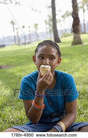 Close-up of a girl eating a cupcake at a park View Large Photo Image Stock Image - Close-up of a girl eating a cupcake at a park. Fotosearch