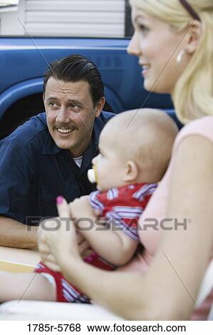 Stock Photo - Close-up of a man sitting next to his wife and baby. Fotosearch