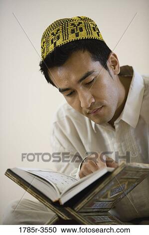 Stock Image - Close-up of a Muslim man reading Koran. Fotosearch