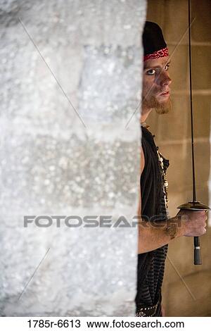 Close-up of a pirate brandishing a sword hiding behind a castle wall View Large Photo Image Stock Image - Close-up of a pirate brandishing a sword hiding behind a castle wall. Fotosearch