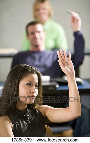 Stock Image - Close-up of a student with her hand raised. Fotosearch