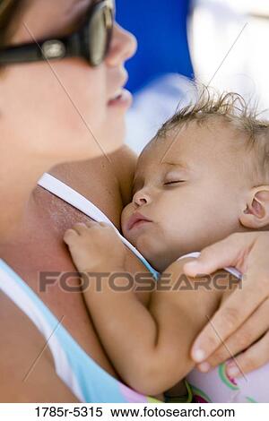 Close-up of a young mother holding sleeping baby tightly against her chest View Large Photo Image Stock Photography - Close-up of a young mother holding sleeping baby tightly against her chest. Fotosearch