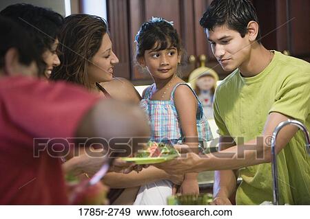 Close up of family in kitchen serving food View Large Photo Image Stock Photo - Close up of family in kitchen serving food. Fotosearch