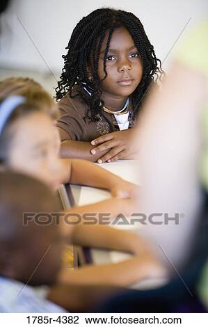 Stock Image - Close up of girl paying attention in class. Fotosearch