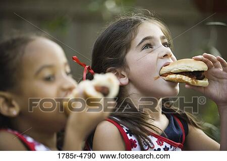 Stock Image - Close-up of girls eating hotdogs. Fotosearch