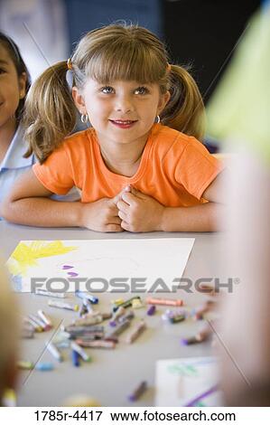Stock Photo - Close up of little girl looking up at teacher in class. Fotosearch