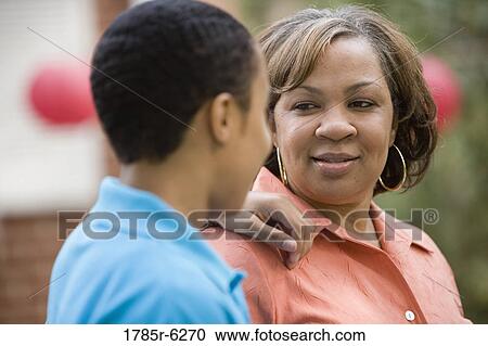 Close-up of mature woman looking at and listening to her son View Large Photo Image Stock Image - Close-up of mature woman looking at and listening to her son. Fotosearch