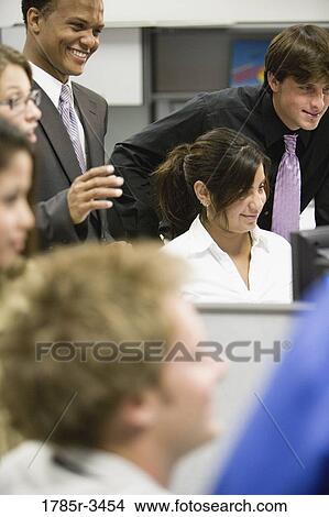 Picture - Close-up of office workers gathered around computer. Fotosearch