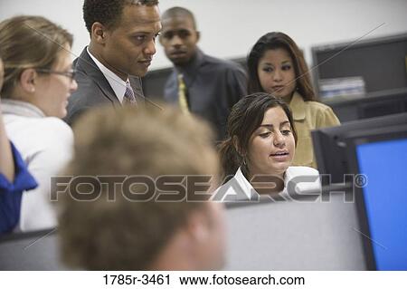 Stock Image - Close-up of office workers gathered around computer. Fotosearch