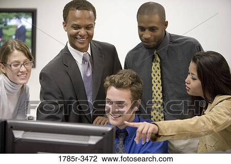 Close-up of office workers gathered around computer View Large Photo Image Stock Image - Close-up of office workers gathered around computer. Fotosearch