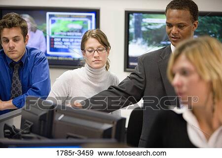 Stock Photo - Close-up of office workers gathered around computer. Fotosearch