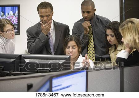 Stock Photo - Close-up of office workers gathered around computer. Fotosearch