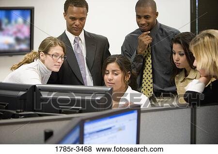 Stock Photo - Close-up of office workers gathered around computer. Fotosearch