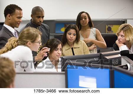 Stock Photograph - Close-up of office workers gathered around computer. Fotosearch