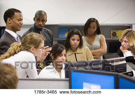 Stock Photography - Close-up of office workers gathered around computer. Fotosearch
