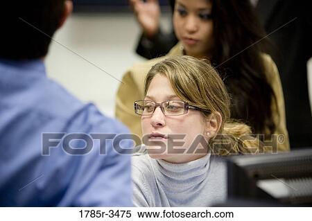 Stock Photography - Close-up of office workers gathered around computer. Fotosearch