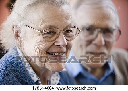 Close-up of senior woman smiling with senior man in background View Large Photo Image Picture - Close-up of senior woman smiling with senior man in background. Fotosearch
