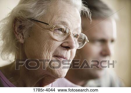 Close-up of smiling senior woman with man in background View Large Photo Image Picture - Close-up of smiling senior woman with man in background. Fotosearch