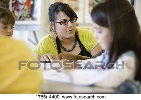 Close up of teacher helping young children in class View Large Photo Image Stock Image - Close up of teacher helping young children in class. Fotosearch