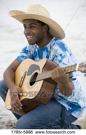 Close up of young man playing guitar on the beach View Large Photo Image Stock Photograph - Close up of young man playing guitar on the beach. Fotosearch