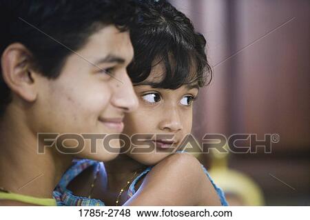 Stock Photo - Close up side view of a teen boy holding his sister. Fotosearch