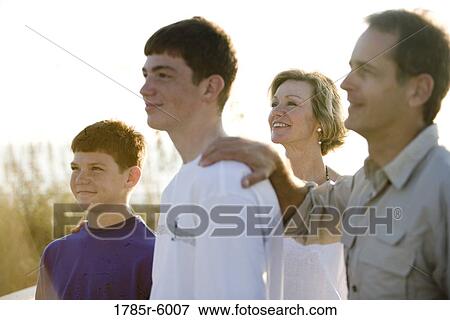 Stock Photo - Close-up view of a family with two teenage boys silhouetted against a bright sky. Fotosearch