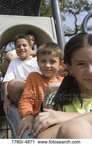 Close-up view of laughing children sitting on a slide at a playground View Large Photo Image Stock Image - Close-up view of laughing children sitting on a slide at a playground. Fotosearch