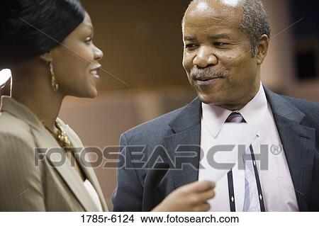 Picture - Close-up view of mature businessman talking to a younger woman. Fotosearch