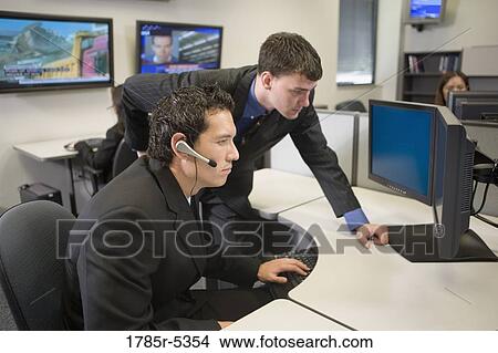 Picture - Co-workers in an office looking at a computer screen. Fotosearch