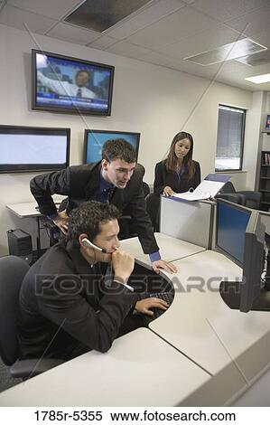 Stock Photography - Co-workers in an office looking at a computer screen. Fotosearch