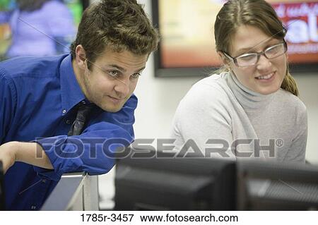 Stock Photo - Co-workers looking at computer monitor. Fotosearch