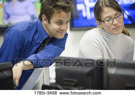 Stock Photo - Co-workers looking at computer monitor. Fotosearch
