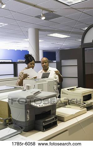 Co-workers using office equipment View Large Photo Image Stock Photo - Co-workers using office equipment. Fotosearch