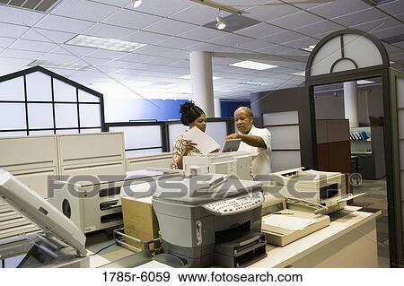 Co-workers using office equipment View Large Photo Image Stock Photo - Co-workers using office equipment. Fotosearch