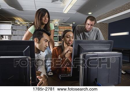 Stock Image - College students using computers in the library. Fotosearch