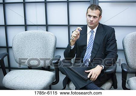 Stock Photography - Contemplative businessman seated in a waiting room. Fotosearch
